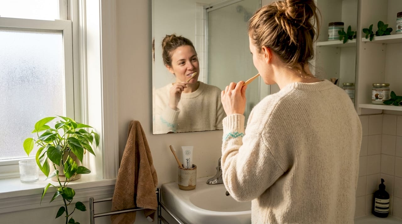 Woman brushing teeth at home bathroom sink