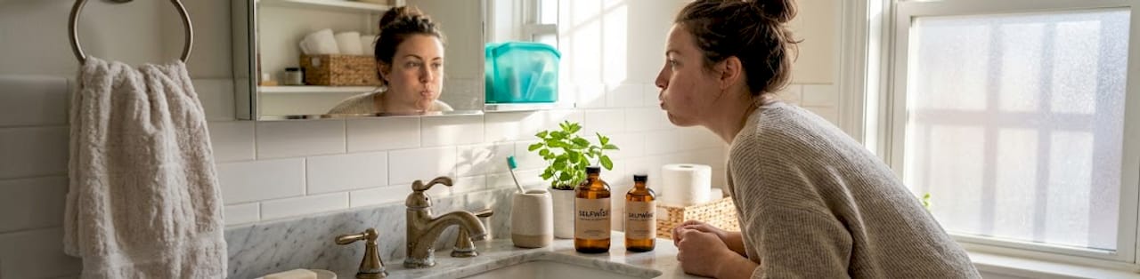 Woman using oil pulling mouthwash in bathroom