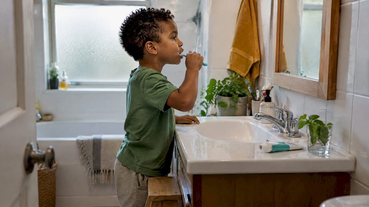Child brushing teeth at a bathroom sink