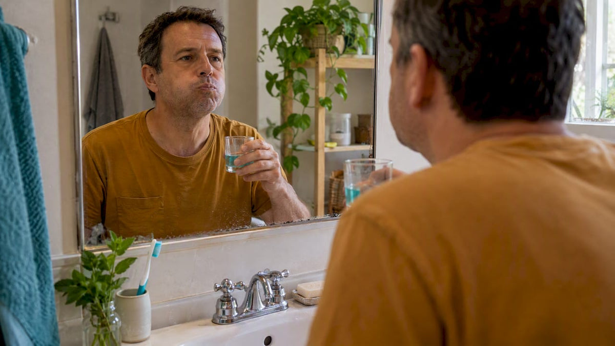 Adult rinsing mouthwash at a bathroom sink